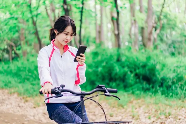 スマホを見ながら自電車に乗っている女性